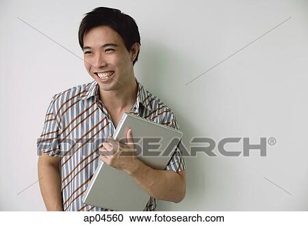 Man holding laptop, smiling View Large Photo Image Stock Image - Man holding laptop, smiling. Fotosearch