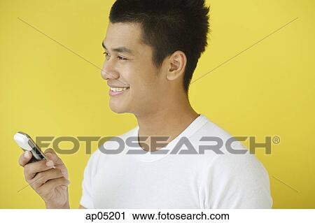 Stock Image - Man holding mobile phone, looking away. Fotosearch