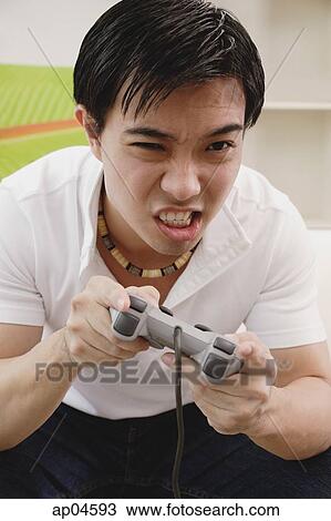 Man holding video game console, grimacing View Large Photo Image Stock Image - Man holding video game console, grimacing. Fotosearch