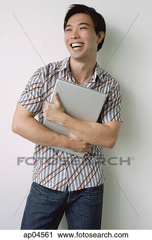 Stock Image - Man hugging laptop, smiling. Fotosearch