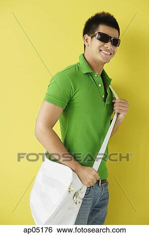 Man in green polo shirt, standing against yellow background, sunglasses on View Large Photo Image Stock Photograph - Man in green polo shirt, standing against yellow background, sunglasses on. Fotosearch