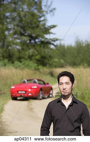 Man looking at camera, red sports car in the background View Large Photo Image Stock Image - Man looking at camera, red sports car in the background. Fotosearch