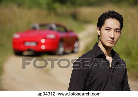 Man looking at camera, red sports car in the background, portrait View Large Photo Image Stock Image - Man looking at camera, red sports car in the background, portrait. Fotosearch