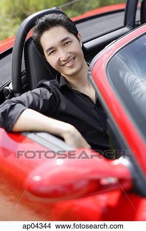Man sitting in red convertible car, smiling at camera View Large Photo Image Picture - Man sitting in red convertible car, smiling at camera. Fotosearch