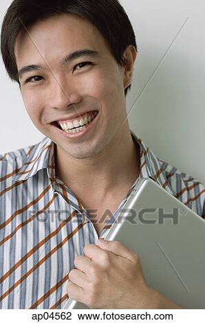 Man smiling at camera, holding laptop View Large Photo Image Stock Image - Man smiling at camera, holding laptop. Fotosearch