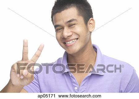 Man smiling at camera, making peace hand sign View Large Photo Image Stock Image - Man smiling at camera, making peace hand sign. Fotosearch