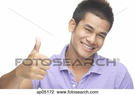 Stock Image - Man smiling at camera, making thumbs up sign. Fotosearch