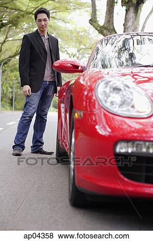 Man standing and looking at rear of red sports car View Large Photo Image Stock Photo - Man standing and looking at rear of red sports car. Fotosearch