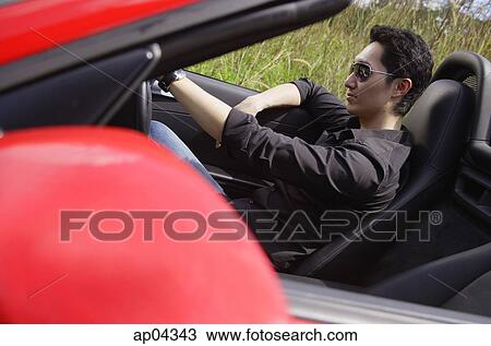 Man wearing sunglasses, driving red convertible sports car View Large Photo Image Stock Image - Man wearing sunglasses, driving red convertible sports car. Fotosearch