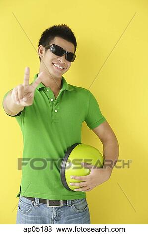 Stock Photo - Man wearing sunglasses, making peace sign. Fotosearch