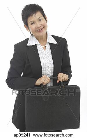 Stock Image - Mature businesswoman with briefcase, smiling at camera. Fotosearch