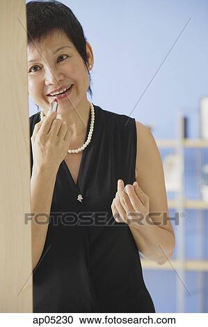 Mature woman applying lipstick View Large Photo Image Stock Image - Mature woman applying lipstick. Fotosearch
