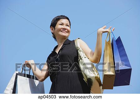 Mature woman carrying shopping bags, looking away View Large Photo Image Stock Image - Mature woman carrying shopping bags, looking away. Fotosearch