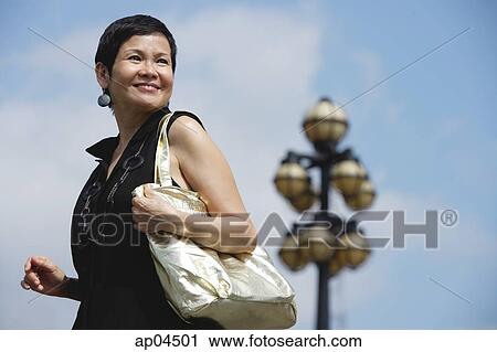 Mature woman carrying shoulder bag View Large Photo Image Stock Image - Mature woman carrying shoulder bag. Fotosearch