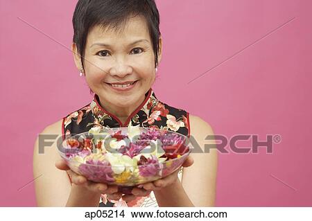 Mature woman holding bowl of flowers View Large Photo Image Picture - Mature woman holding bowl of flowers. Fotosearch