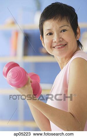 Mature woman holding dumbbells View Large Photo Image Stock Image - Mature woman holding dumbbells. Fotosearch