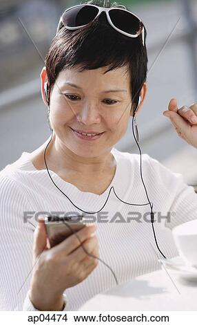 Mature woman listening to music from an MP3 player View Large Photo Image Picture - Mature woman listening to music from an MP3 player. Fotosearch