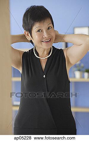 Mature woman putting on pearl necklace View Large Photo Image Stock Photo - Mature woman putting on pearl necklace. Fotosearch