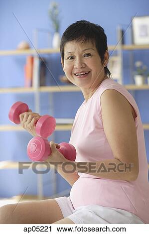 Mature woman using dumbbells at home View Large Photo Image Stock Image - Mature woman using dumbbells at home. Fotosearch