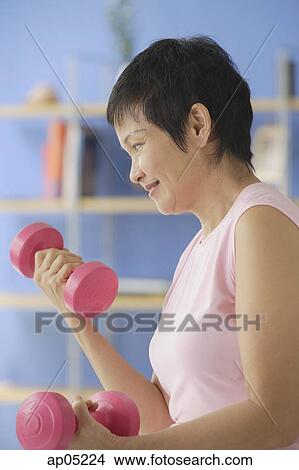 Picture - Mature woman using dumbbells. Fotosearch