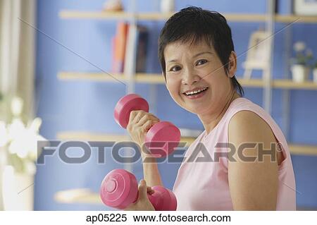 Mature woman using dumbbells, smiling at camera View Large Photo Image Stock Photography - Mature woman using dumbbells, smiling at camera. Fotosearch