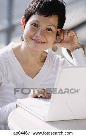 Mature woman with laptop, smiling at camera View Large Photo Image Stock Photo - Mature woman with laptop, smiling at camera. Fotosearch