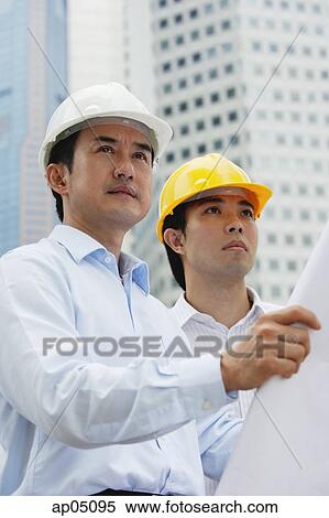 Men in hardhats, holding blueprints, buildings in the background View Large Photo Image Stock Photography - Men in hardhats, holding blueprints, buildings in the background. Fotosearch
