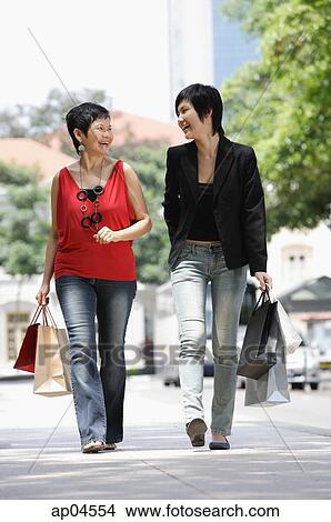 Mother and adult daughter walking in city, carrying shopping bags View Large Photo Image Picture - Mother and adult daughter walking in city, carrying shopping bags. Fotosearch