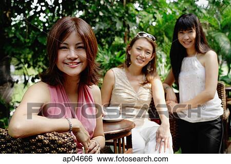 Three women at outdoor garden cafe, smiling at camera, portrait View Large Photo Image Stock Photograph - Three women at outdoor garden cafe, smiling at camera, portrait. Fotosearch