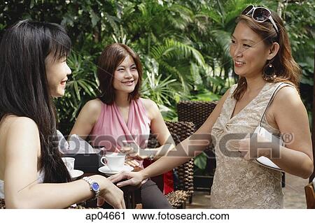 Three women talking at outdoor garden cafe View Large Photo Image Stock Image - Three women talking at outdoor garden cafe. Fotosearch