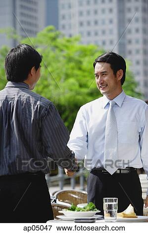 Two businessman at outdoor cafe, shaking hands View Large Photo Image Stock Photo - Two businessman at outdoor cafe, shaking hands. Fotosearch