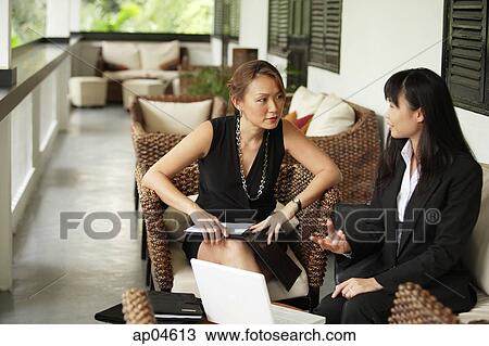 Two businesswomen sitting on patio having a discussion View Large Photo Image Stock Image - Two businesswomen sitting on patio having a discussion. Fotosearch