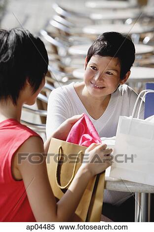Two women at cafe, with shopping bags View Large Photo Image Stock Photography - Two women at cafe, with shopping bags. Fotosearch