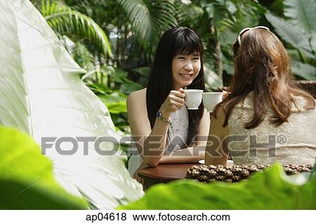 Stock Photo - Two women at outdoor garden cafe, having a drink. Fotosearch