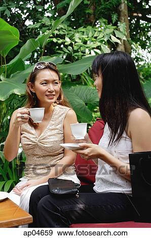 Stock Photo - Two women at outdoor garden cafe, having coffee. Fotosearch
