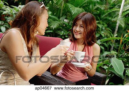 Two women having drinks in the garden View Large Photo Image Stock Photo - Two women having drinks in the garden. Fotosearch