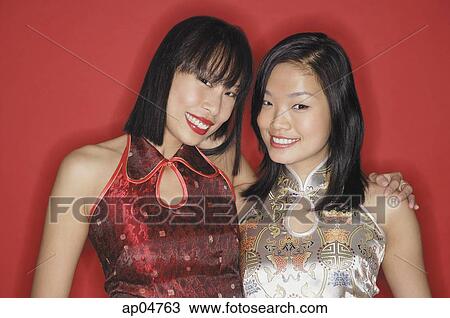Stock Image - Two women in cheongsams, smiling at camera. Fotosearch