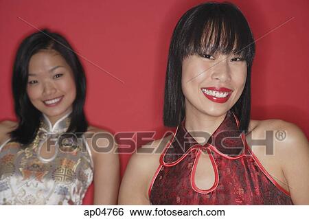Stock Photograph - Two women, red background, looking at camera. Fotosearch