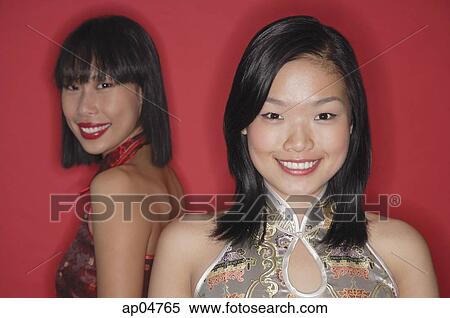 Stock Photography - Two women, red background, smiling at camera. Fotosearch