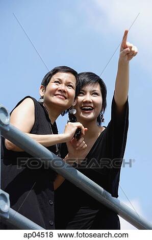 Two women side by side, one pointing in the distance View Large Photo Image Stock Photo - Two women side by side, one pointing in the distance. Fotosearch