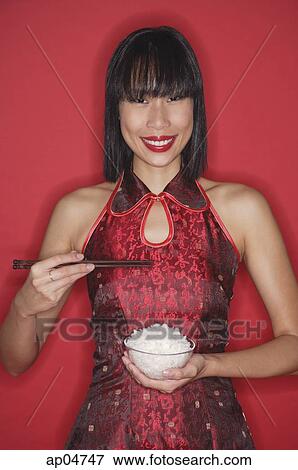 Woman against red background, dressed in cheongsam, holding bowl of rice View Large Photo Image Stock Photo - Woman against red background, dressed in cheongsam, holding bowl of rice. Fotosearch