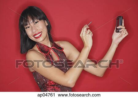 Woman against red background, holding PDA, smiling at camera View Large Photo Image Stock Image - Woman against red background, holding PDA, smiling at camera. Fotosearch