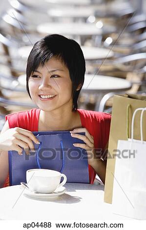 Woman at cafe, holding shopping bag View Large Photo Image Stock Photo - Woman at cafe, holding shopping bag. Fotosearch