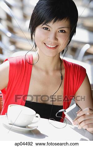 Stock Image - Woman at cafe, listening to MP3 player. Fotosearch