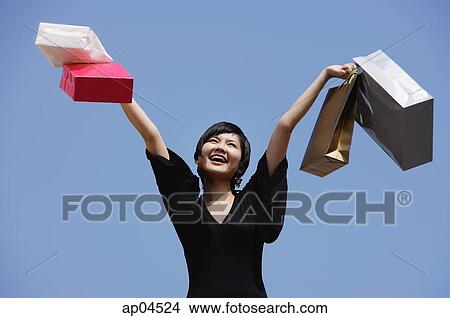 Woman carrying shopping bags, arms outstretched View Large Photo Image Picture - Woman carrying shopping bags, arms outstretched. Fotosearch