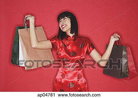 Stock Image - Woman carrying shopping bags, smiling. Fotosearch