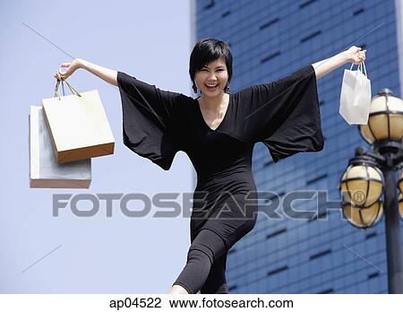 Woman dressed in black, arms outstretched, carrying shopping bags View Large Photo Image Stock Image - Woman dressed in black, arms outstretched, carrying shopping bags. Fotosearch