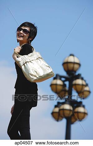 Stock Photo - Woman dressed in black, carrying bag over shoulder. Fotosearch