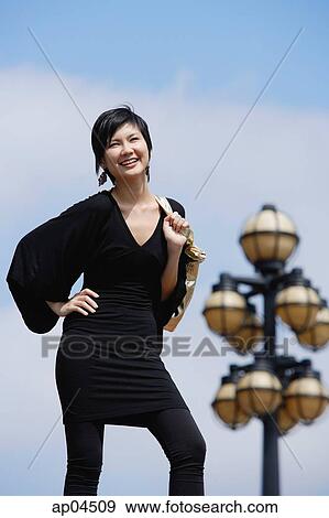 Woman dressed in black, carrying bag over shoulder, smiling at camera View Large Photo Image Stock Photo - Woman dressed in black, carrying bag over shoulder, smiling at camera. Fotosearch