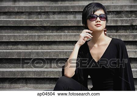 Picture - Woman dressed in black, wearing large sunglasses. Fotosearch